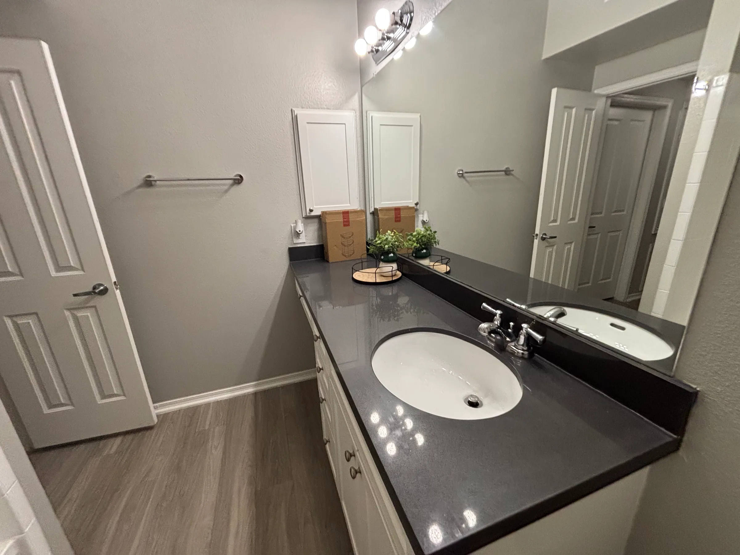 Clean modern bathroom with dark countertop, white sink, and chrome fixtures.
